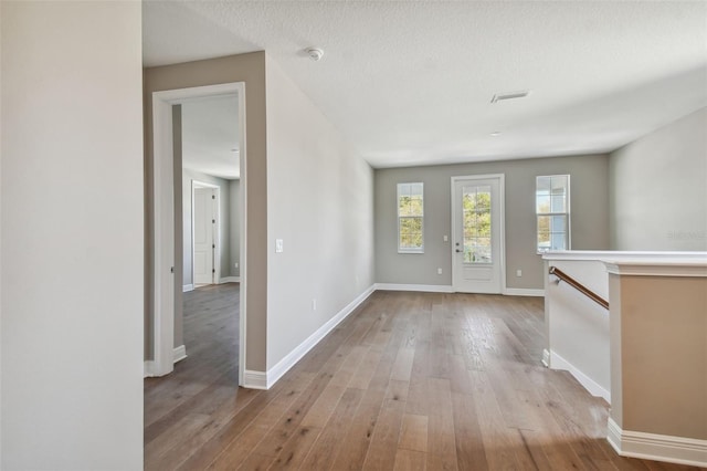 entryway with a textured ceiling and light hardwood / wood-style flooring