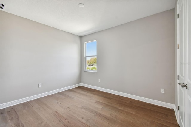 empty room with light hardwood / wood-style floors and a textured ceiling