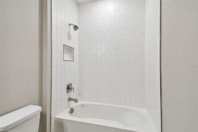 bathroom with tiled shower / bath combo and toilet