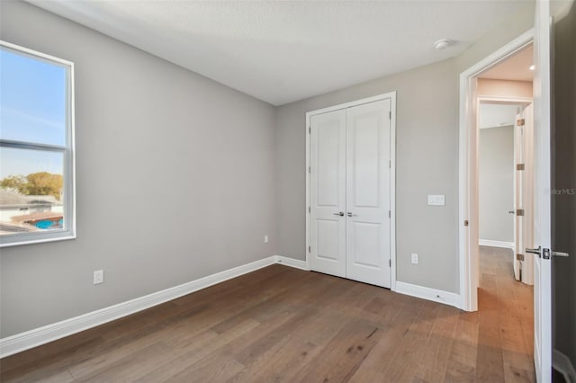 unfurnished bedroom featuring dark wood-type flooring and a closet