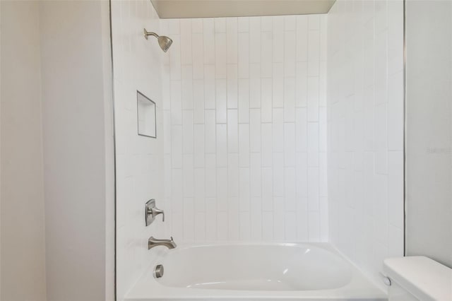 bathroom with toilet and tiled shower / bath combo