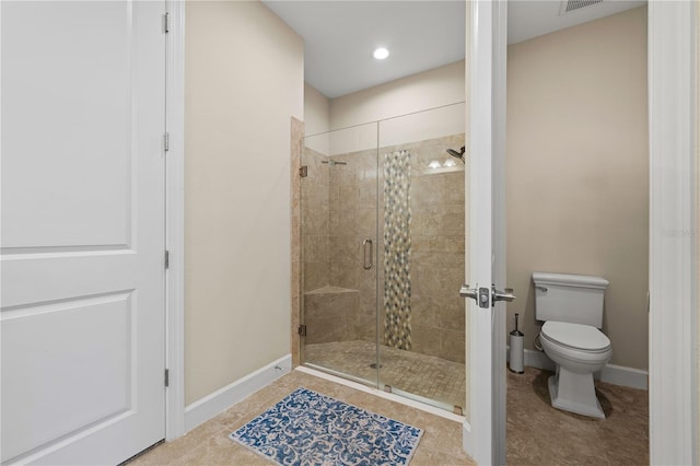 bathroom featuring a shower with door, tile patterned flooring, and toilet