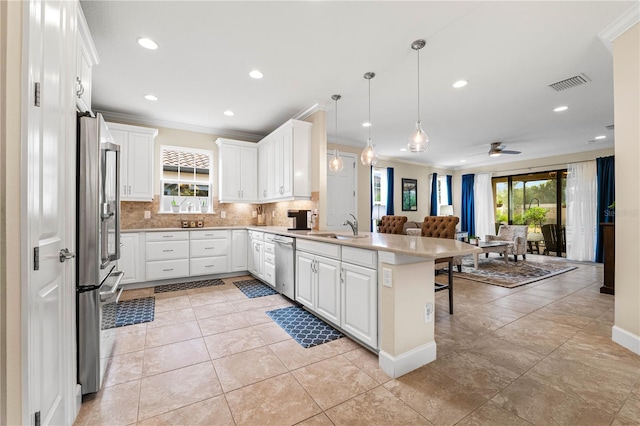 kitchen with white cabinetry, hanging light fixtures, stainless steel appliances, a kitchen breakfast bar, and kitchen peninsula