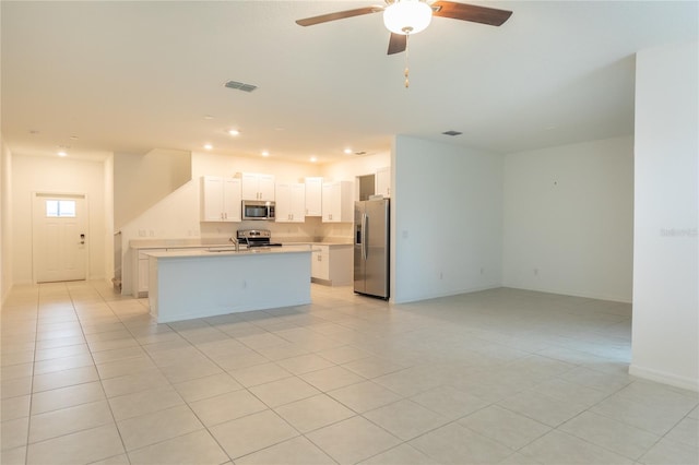 kitchen with light tile patterned flooring, a kitchen island with sink, stainless steel appliances, open floor plan, and light countertops