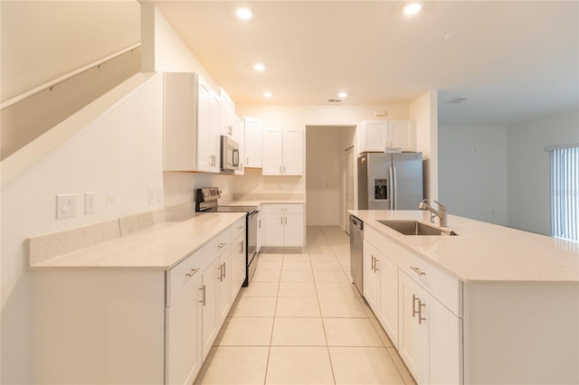 kitchen featuring light tile patterned floors, white cabinets, stainless steel appliances, a sink, and recessed lighting