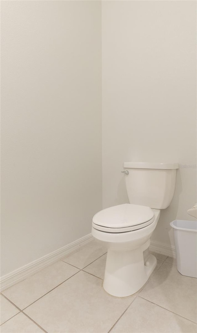 bathroom with tile patterned flooring, baseboards, and toilet