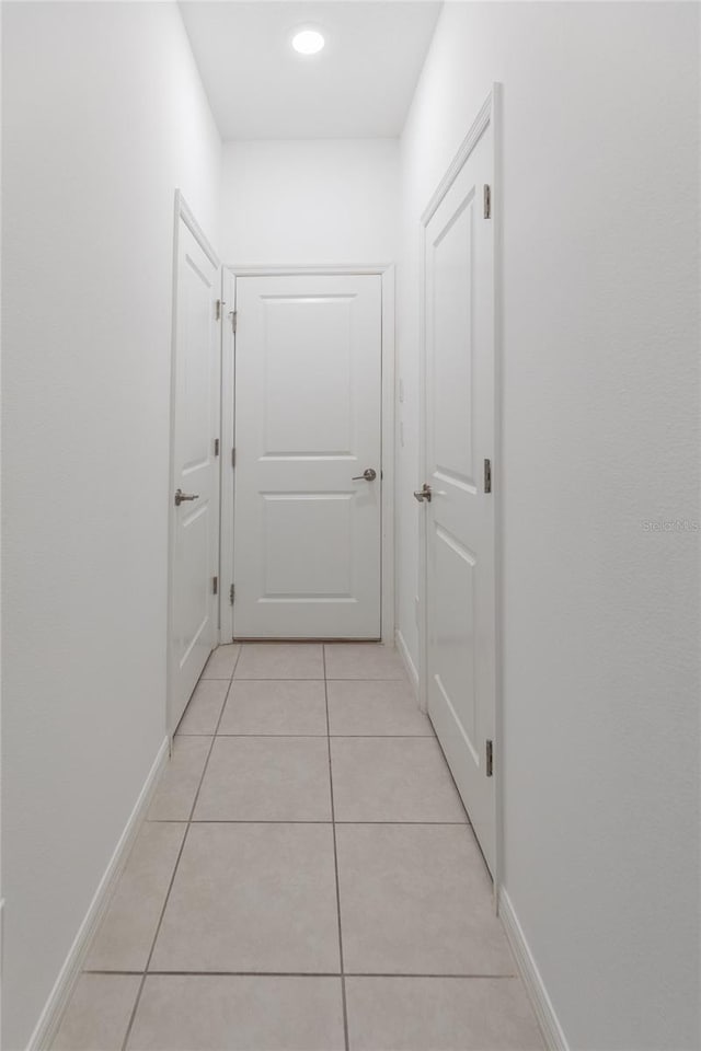 hall with light tile patterned flooring and baseboards