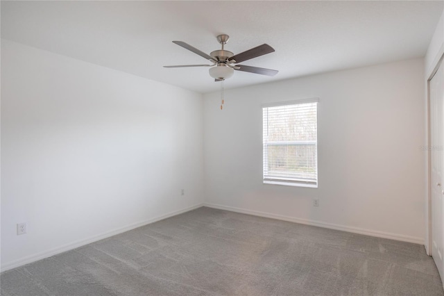 carpeted empty room with a ceiling fan and baseboards