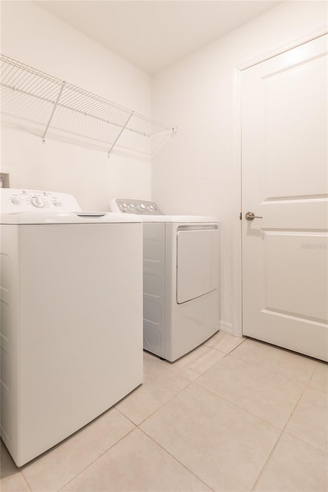 laundry room featuring laundry area, light tile patterned flooring, and washing machine and clothes dryer