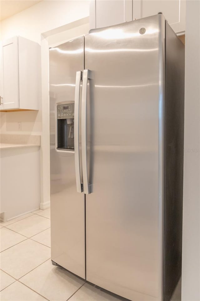 interior space with light countertops, stainless steel fridge, and white cabinetry