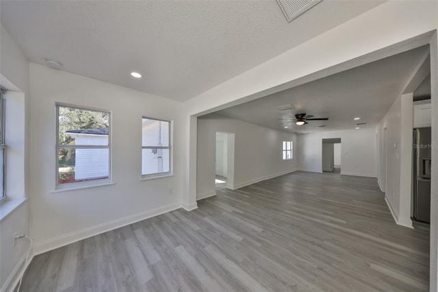 unfurnished living room featuring ceiling fan, a textured ceiling, and light wood-type flooring