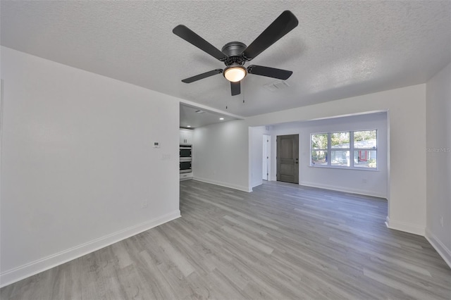 unfurnished living room featuring ceiling fan, light hardwood / wood-style flooring, and a textured ceiling