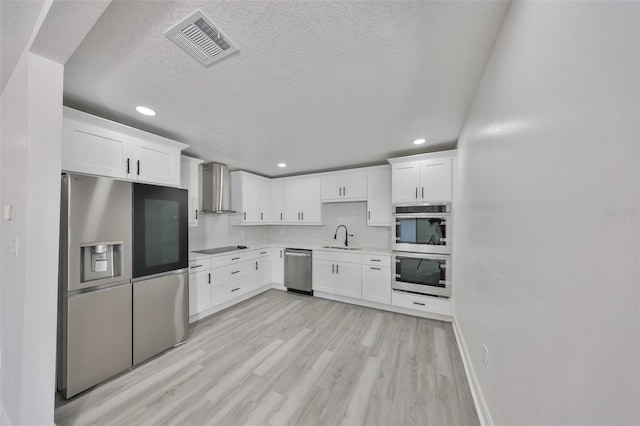 kitchen featuring white cabinetry, appliances with stainless steel finishes, sink, and wall chimney exhaust hood