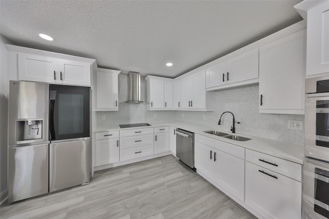 kitchen featuring white cabinetry, appliances with stainless steel finishes, sink, and wall chimney range hood