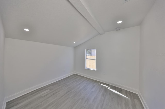 empty room with vaulted ceiling with beams and light wood-type flooring