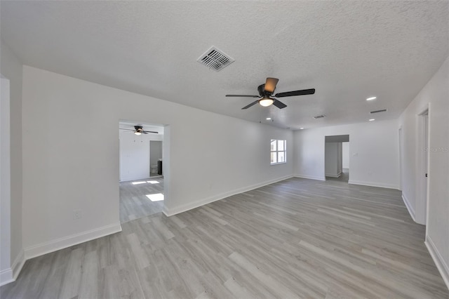 spare room with ceiling fan, a textured ceiling, and light wood-type flooring