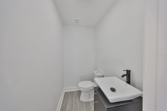 bathroom featuring vanity, wood-type flooring, and toilet