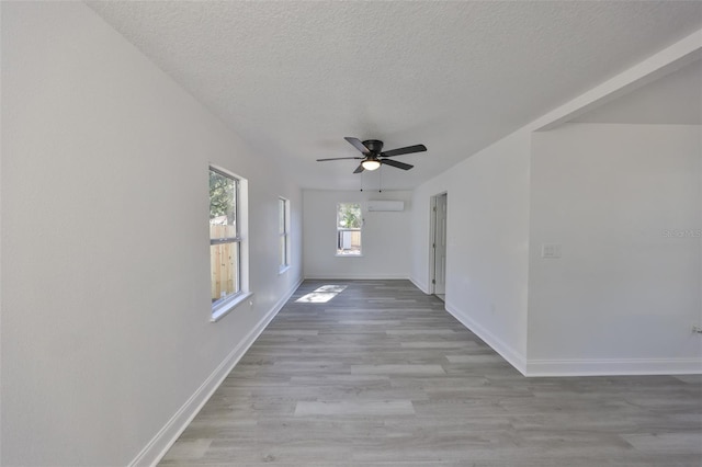 interior space featuring a wall mounted air conditioner, light hardwood / wood-style floors, and a textured ceiling