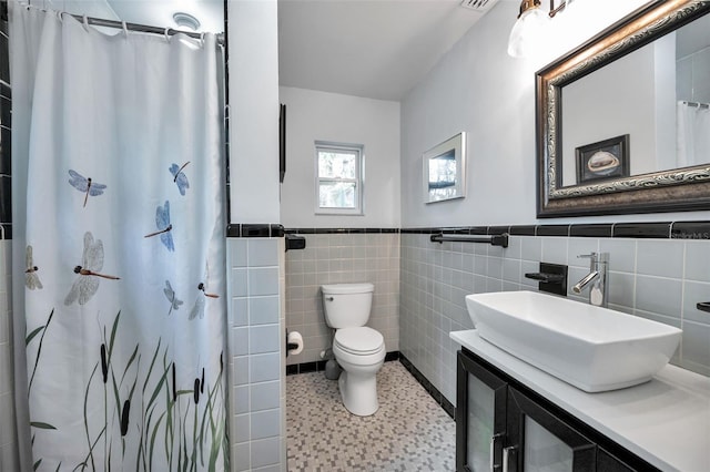 bathroom with toilet, tile walls, vanity, and a shower with shower curtain