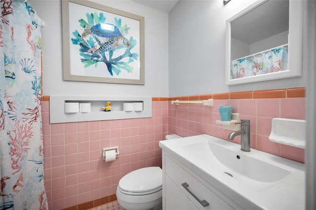 bathroom with vanity, toilet, and tile walls