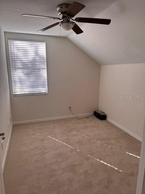 additional living space featuring ceiling fan, vaulted ceiling, carpet floors, and a textured ceiling