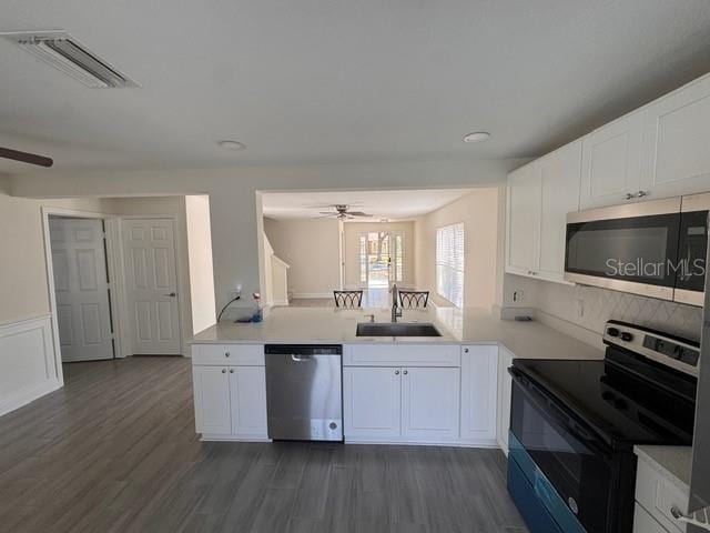 kitchen with appliances with stainless steel finishes, dark wood-type flooring, white cabinets, ceiling fan, and sink