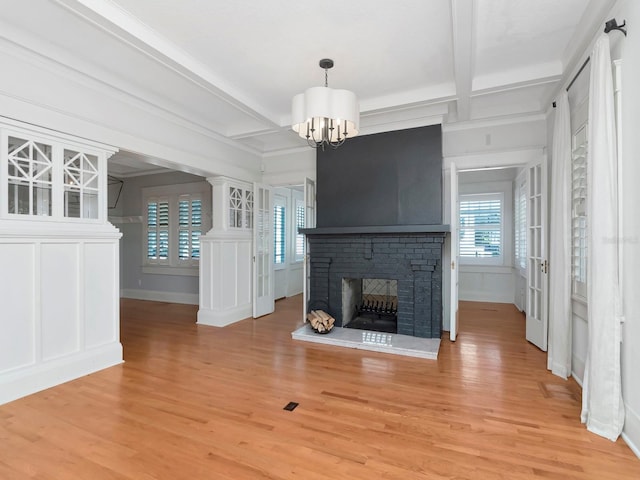 unfurnished living room featuring a fireplace, a chandelier, coffered ceiling, light hardwood / wood-style floors, and beam ceiling