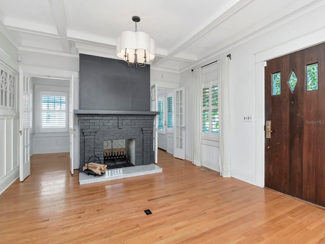 living room featuring a fireplace, wood-type flooring, coffered ceiling, and a notable chandelier