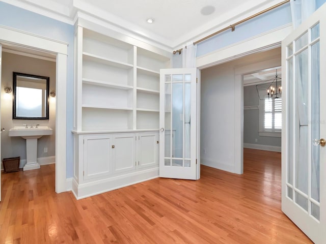 interior space featuring an inviting chandelier, ornamental molding, and light hardwood / wood-style flooring