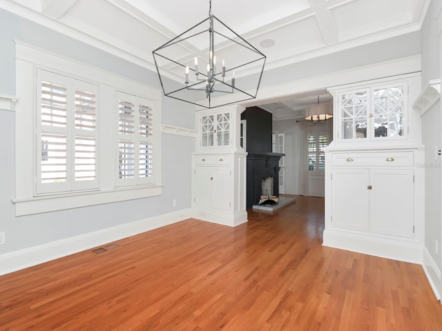 unfurnished dining area with beamed ceiling, coffered ceiling, hardwood / wood-style floors, and a notable chandelier