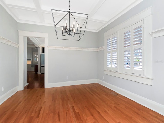 unfurnished dining area featuring beam ceiling, coffered ceiling, hardwood / wood-style floors, and a chandelier