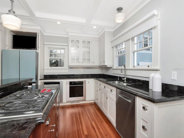 kitchen featuring decorative light fixtures, sink, white cabinets, coffered ceiling, and stainless steel appliances