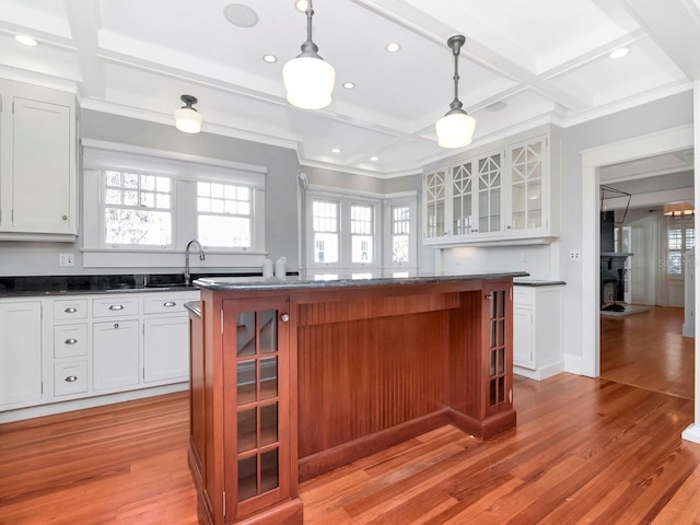 kitchen featuring pendant lighting, light hardwood / wood-style flooring, a kitchen island, and white cabinets