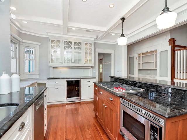 kitchen with appliances with stainless steel finishes, white cabinets, wine cooler, dark stone counters, and hanging light fixtures