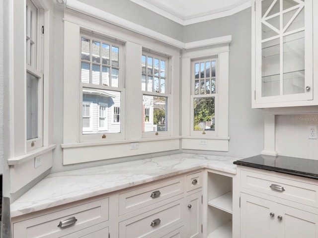 kitchen with white cabinetry, ornamental molding, and light stone counters