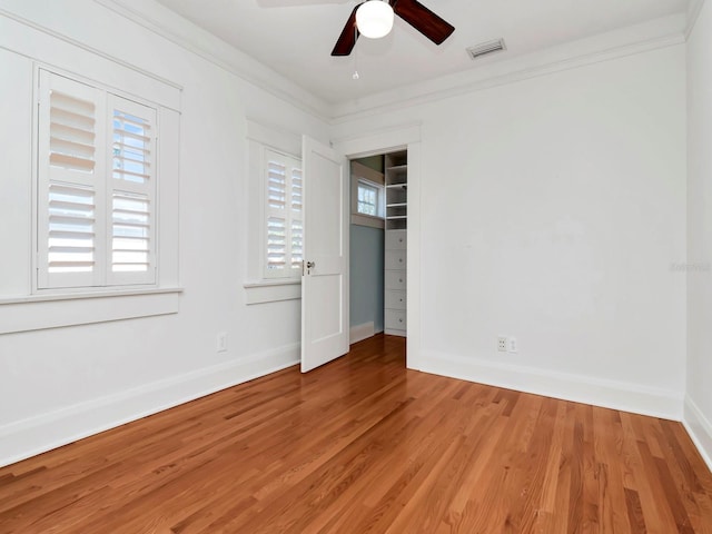 unfurnished bedroom with hardwood / wood-style flooring, ornamental molding, and ceiling fan