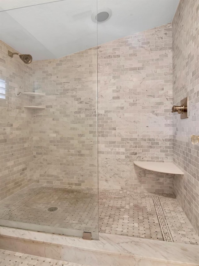 bathroom featuring vaulted ceiling and a tile shower