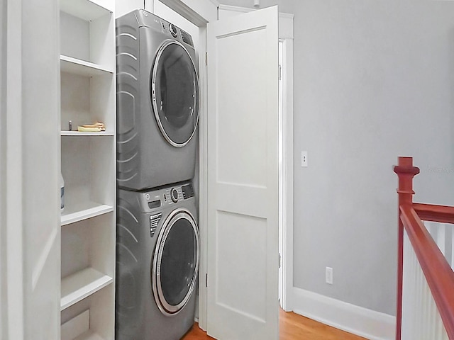 clothes washing area featuring stacked washer / drying machine and light hardwood / wood-style flooring