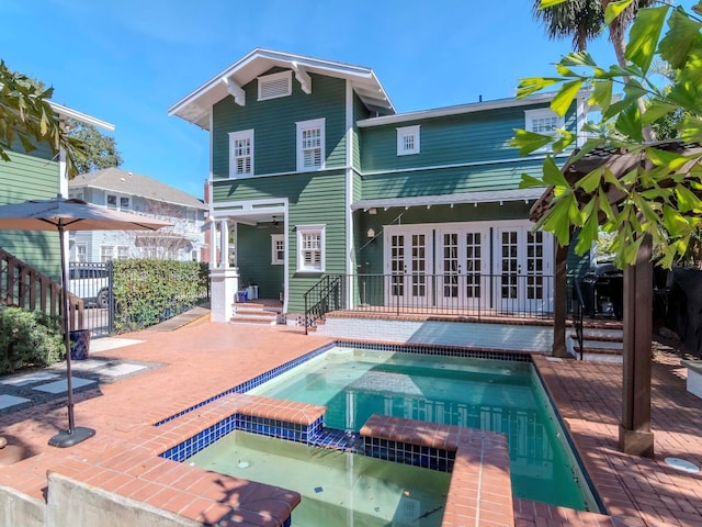 back of property featuring a patio, a pool with hot tub, and french doors