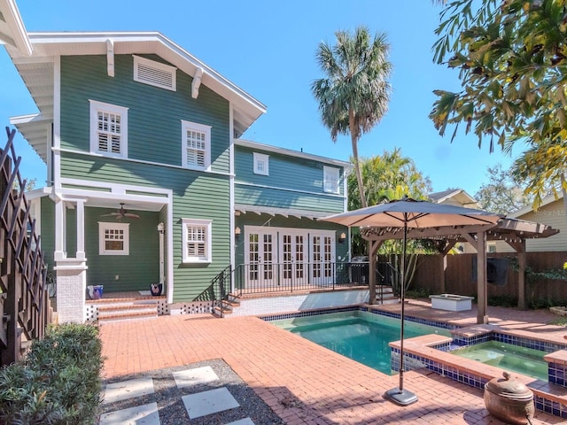 rear view of house with french doors, a gazebo, a pool with hot tub, and a patio