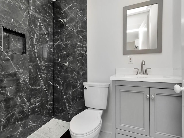 bathroom with vanity, a tile shower, and toilet