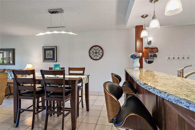 tiled dining area with bar and a textured ceiling