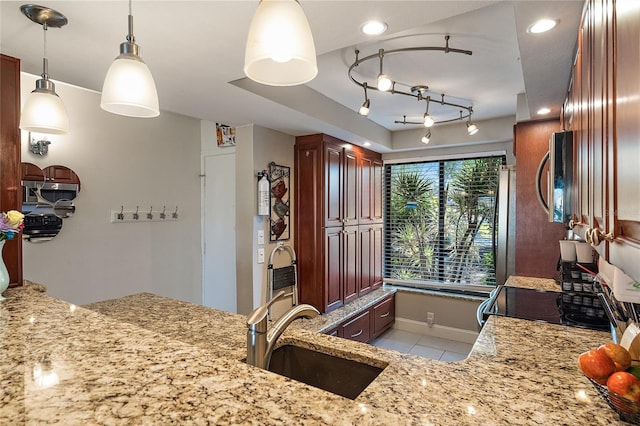 kitchen with pendant lighting, sink, range, light tile patterned floors, and light stone counters