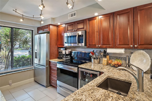 kitchen with light stone countertops, light tile patterned floors, stainless steel appliances, and sink