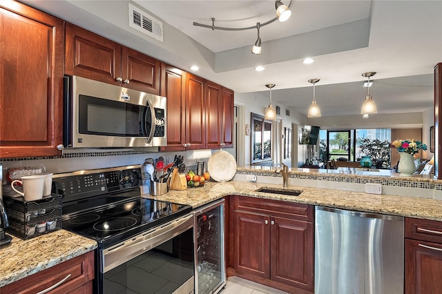 kitchen featuring appliances with stainless steel finishes, sink, beverage cooler, hanging light fixtures, and light stone counters