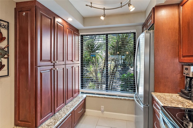 kitchen with light tile patterned flooring, stainless steel fridge, and light stone countertops