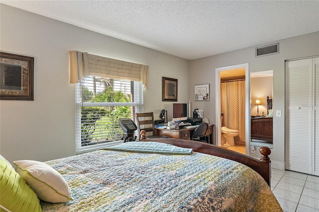 tiled bedroom with connected bathroom and a textured ceiling