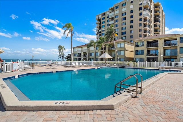 view of swimming pool featuring a water view and a patio area