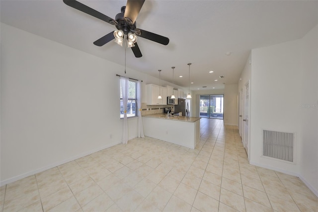 kitchen with hanging light fixtures, a healthy amount of sunlight, white cabinets, and kitchen peninsula