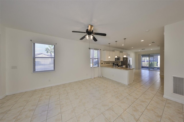 interior space with white cabinetry, dark stone countertops, kitchen peninsula, pendant lighting, and stainless steel appliances